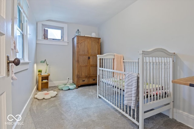 bedroom featuring carpet flooring, a crib, and vaulted ceiling