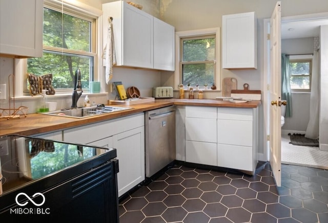 kitchen featuring dishwasher, range with electric cooktop, dark tile patterned flooring, and a healthy amount of sunlight