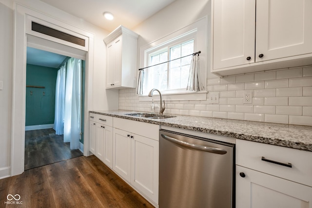 kitchen with light stone counters, dark wood-type flooring, a sink, white cabinets, and stainless steel dishwasher