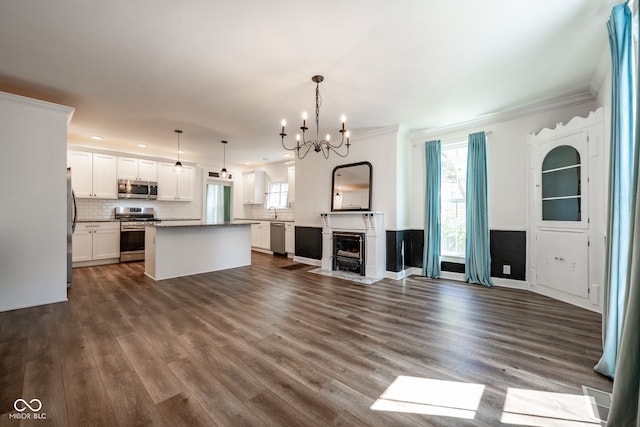 unfurnished living room featuring a notable chandelier, dark hardwood / wood-style flooring, crown molding, sink, and wine cooler