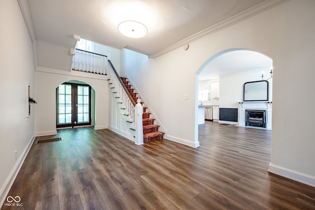 interior space featuring a high ceiling, dark wood-type flooring, french doors, and crown molding