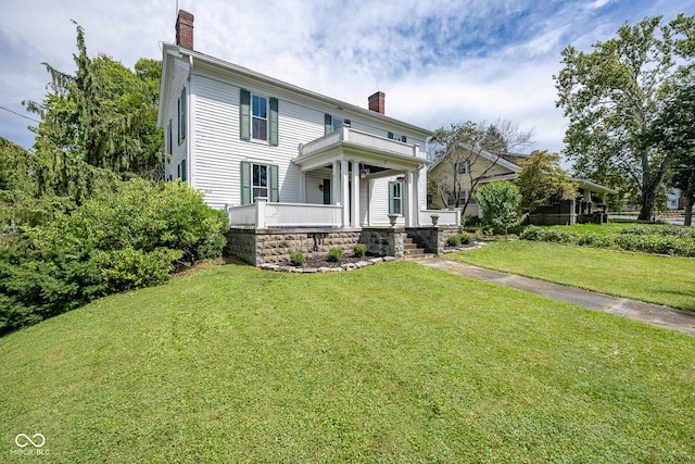 view of front of property featuring a porch, a chimney, and a front lawn