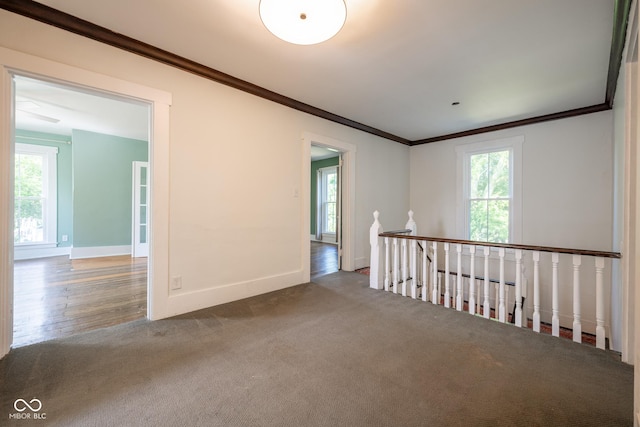 carpeted spare room featuring baseboards and crown molding