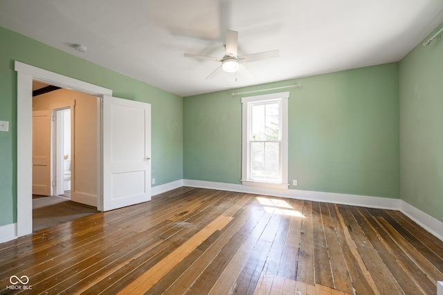 spare room featuring ceiling fan, dark wood-type flooring, and baseboards