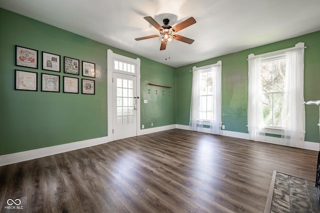 empty room with a wealth of natural light, dark wood-style flooring, and baseboards