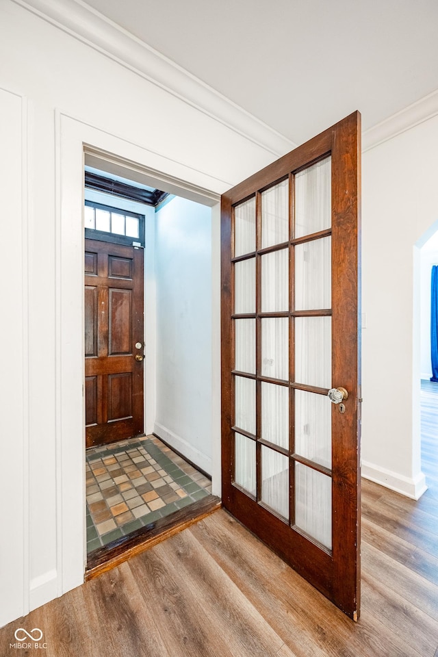 entrance foyer featuring baseboards, ornamental molding, and wood finished floors