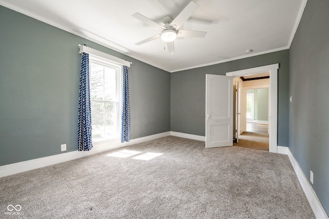 empty room with crown molding, light colored carpet, a wealth of natural light, and ceiling fan