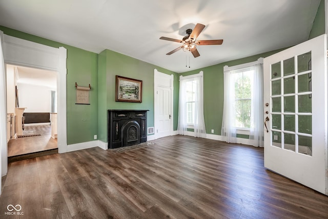 unfurnished living room featuring a ceiling fan, baseboards, and dark wood-style flooring