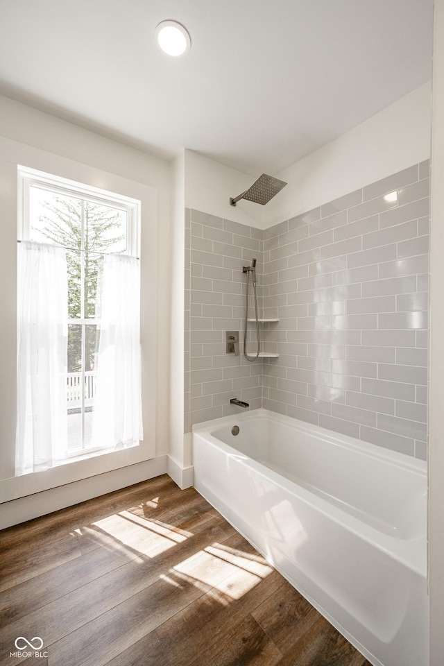 bathroom with washtub / shower combination and wood finished floors