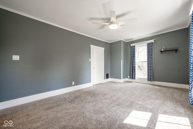 empty room featuring a ceiling fan, carpet, baseboards, and crown molding