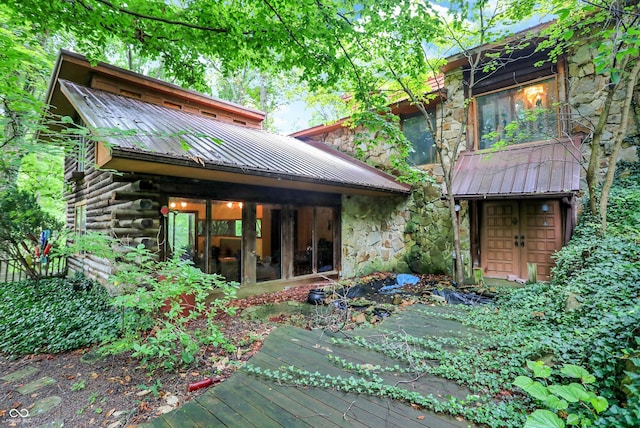 rear view of property with stone siding and metal roof