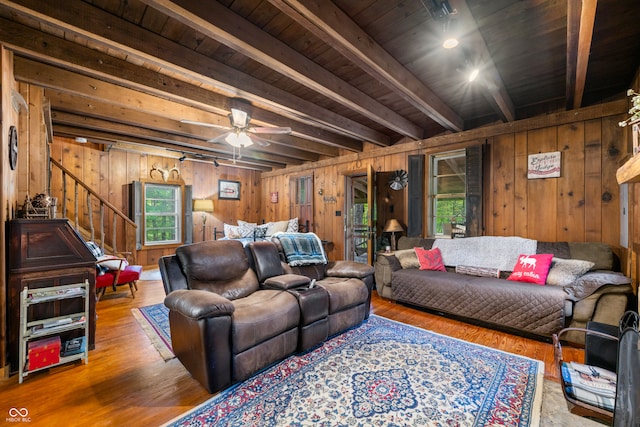 living room featuring wood walls, beam ceiling, ceiling fan, and hardwood / wood-style flooring