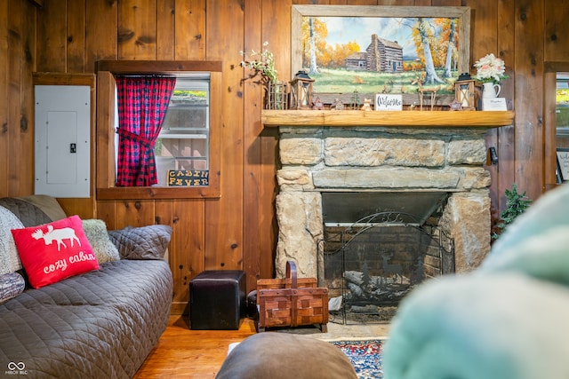 living room featuring a stone fireplace, electric panel, light hardwood / wood-style flooring, and wood walls