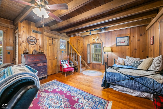 bedroom featuring wood ceiling, wood walls, beam ceiling, ceiling fan, and hardwood / wood-style floors