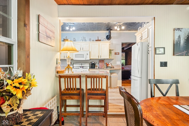 kitchen featuring wood ceiling, white appliances, kitchen peninsula, and light tile patterned floors