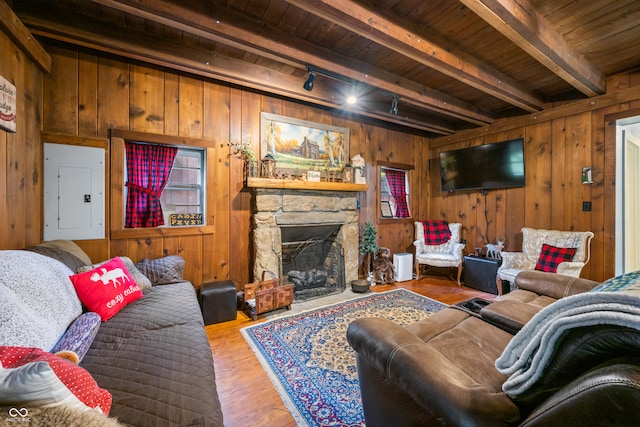 living room with beamed ceiling, hardwood / wood-style flooring, electric panel, wooden walls, and a stone fireplace