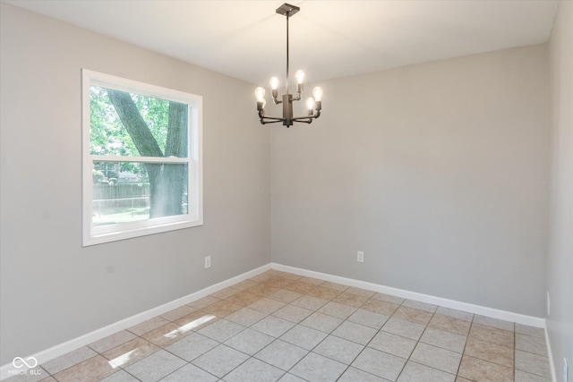 tiled spare room featuring a notable chandelier