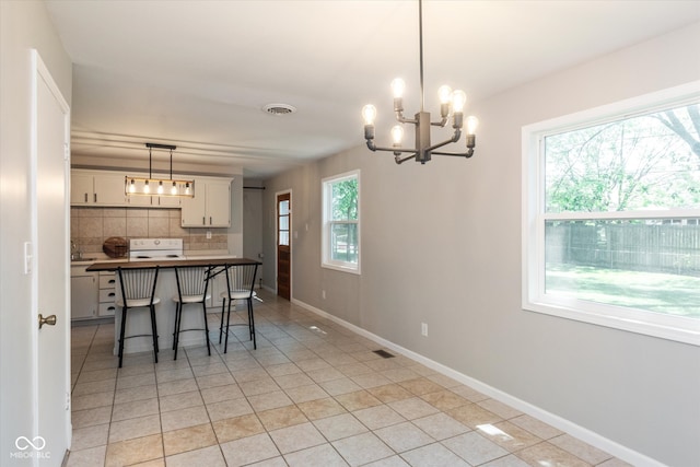 dining space with light tile patterned flooring, sink, and an inviting chandelier