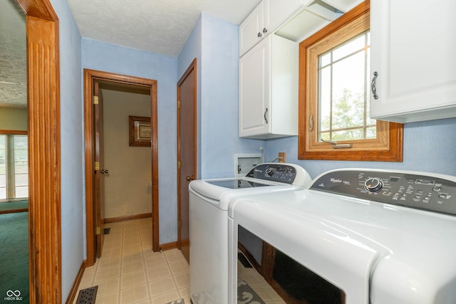 laundry room featuring cabinets, washing machine and clothes dryer, and a textured ceiling