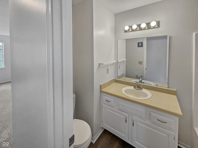 bathroom with hardwood / wood-style floors, toilet, and vanity