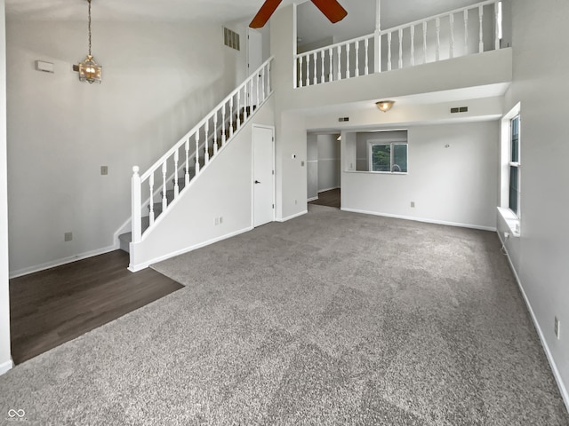 unfurnished living room with ceiling fan, hardwood / wood-style flooring, and a towering ceiling