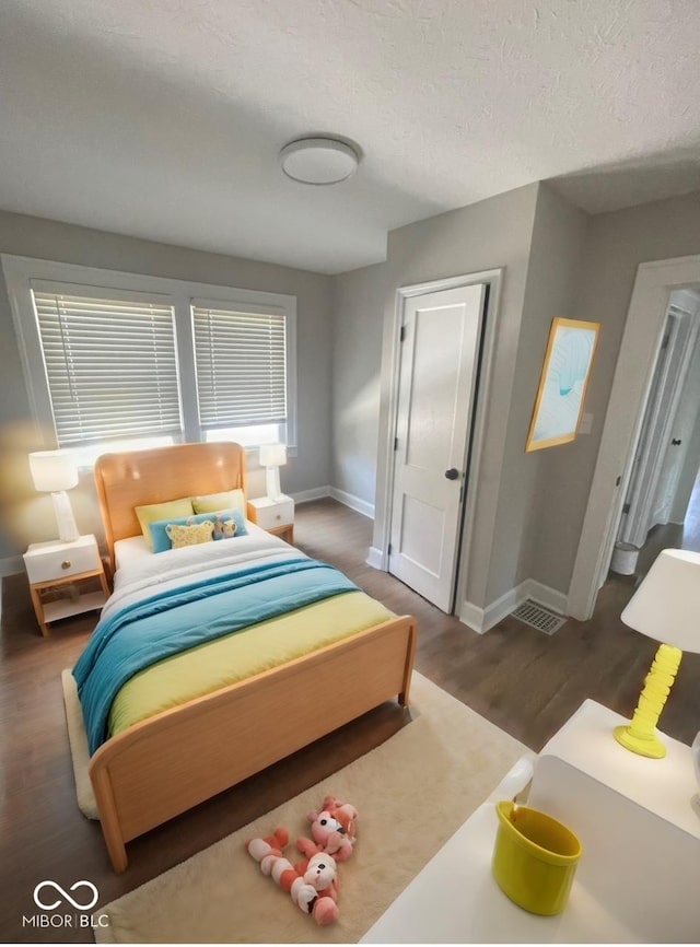 bedroom with dark hardwood / wood-style flooring and a textured ceiling