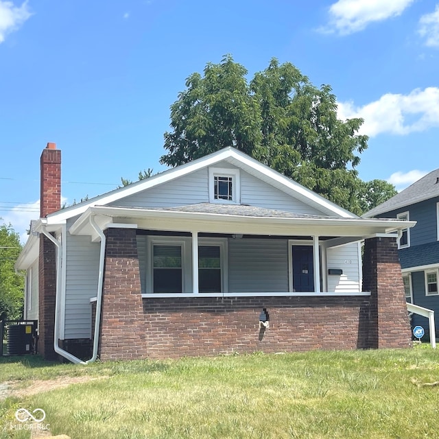 bungalow-style home with cooling unit and a front yard