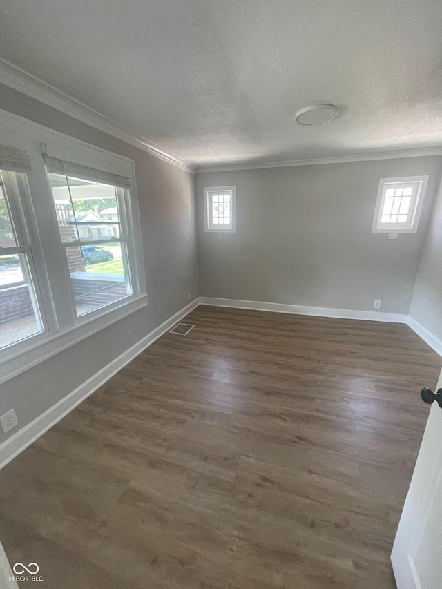 empty room with dark hardwood / wood-style flooring, ornamental molding, and a textured ceiling