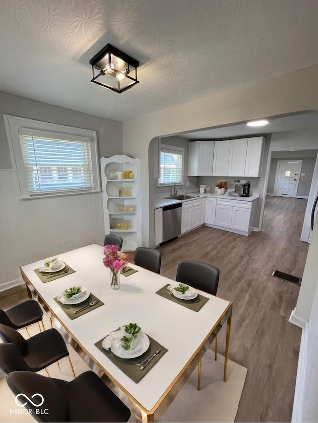 dining room featuring sink, hardwood / wood-style flooring, and a textured ceiling