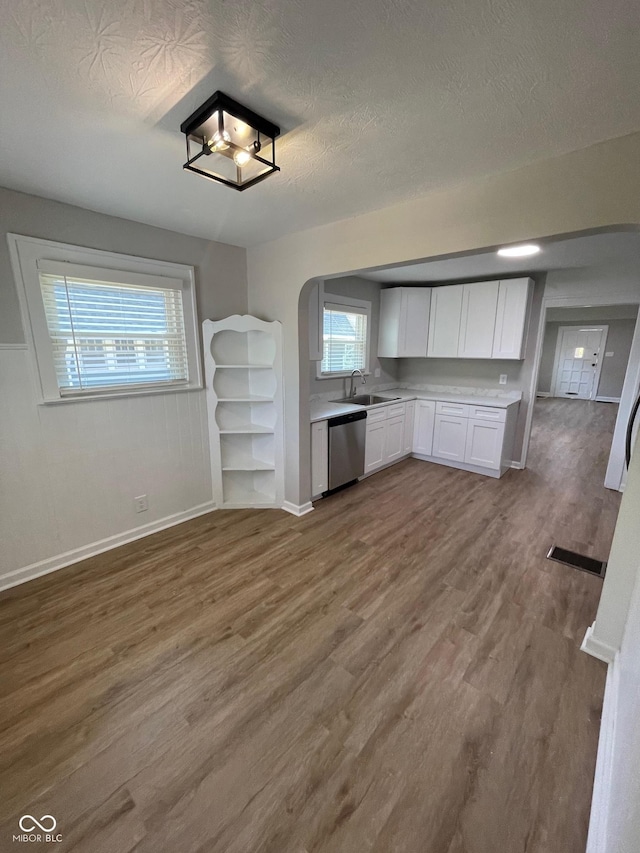 kitchen with hardwood / wood-style floors, sink, white cabinets, stainless steel dishwasher, and a textured ceiling