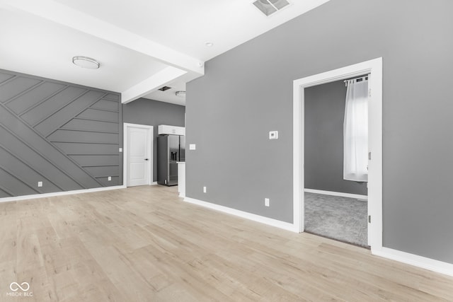 unfurnished living room featuring light hardwood / wood-style flooring and beamed ceiling