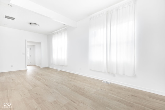 unfurnished room featuring light hardwood / wood-style flooring and beamed ceiling