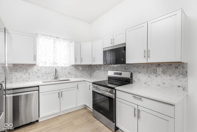 kitchen featuring sink, white cabinetry, light hardwood / wood-style flooring, stainless steel appliances, and decorative backsplash