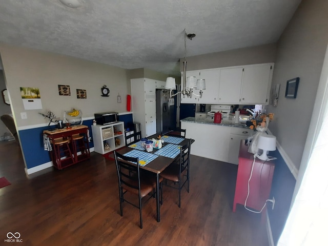 dining space with dark hardwood / wood-style flooring, a chandelier, sink, and a textured ceiling