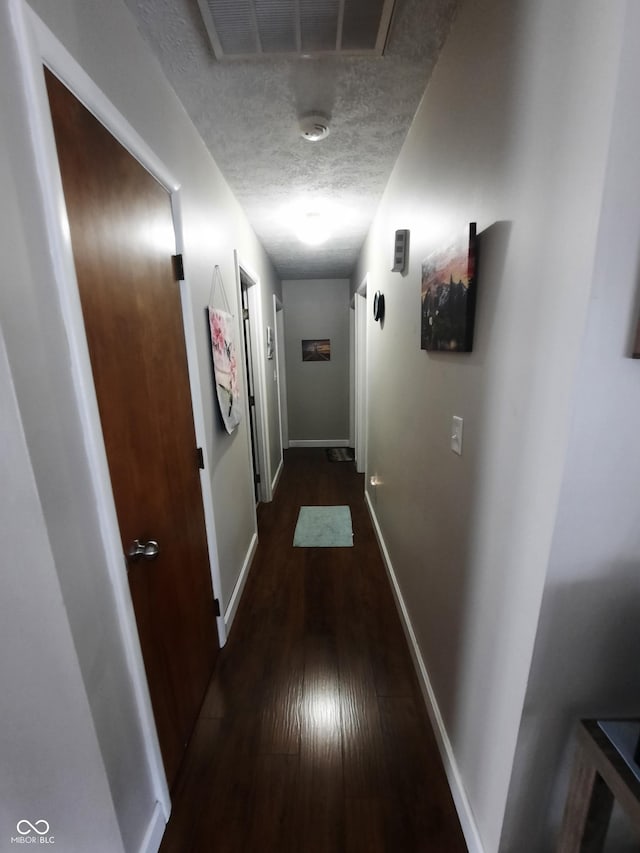 hall featuring dark wood-type flooring and a textured ceiling