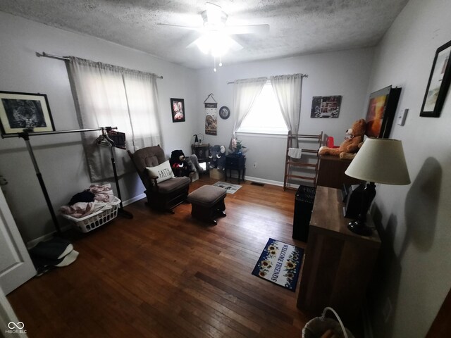 sitting room featuring ceiling fan, hardwood / wood-style flooring, and a textured ceiling