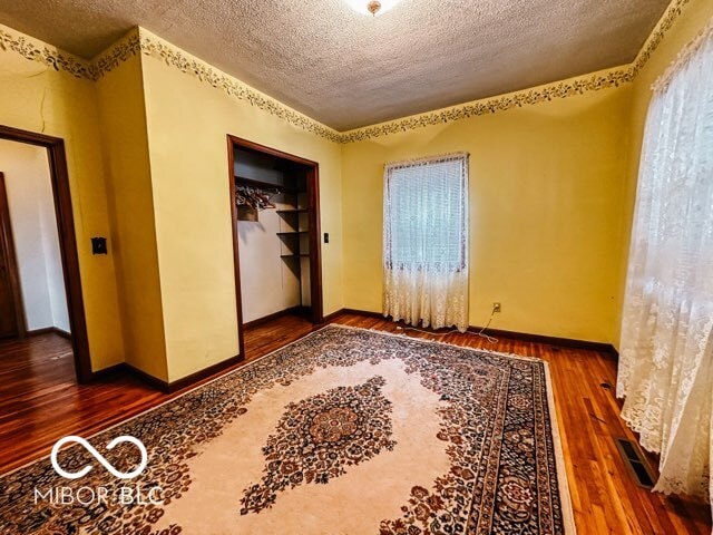 unfurnished room with a textured ceiling, wood-type flooring, and a wealth of natural light