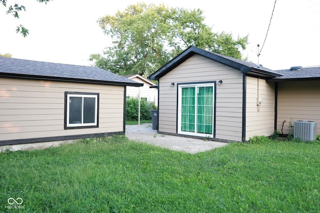 rear view of property with a yard, an outdoor structure, and central air condition unit