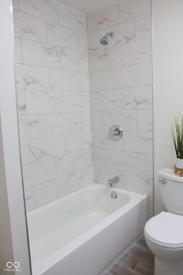 bathroom with tiled shower / bath, wood-type flooring, and toilet