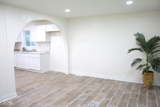 kitchen with white cabinetry, sink, decorative backsplash, and light hardwood / wood-style flooring