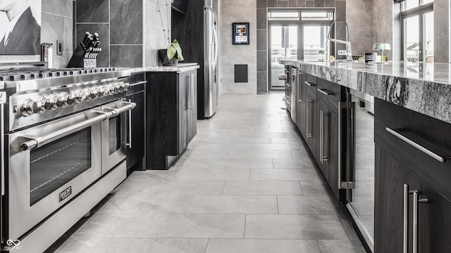 kitchen with light tile patterned flooring, light stone countertops, stainless steel appliances, and backsplash