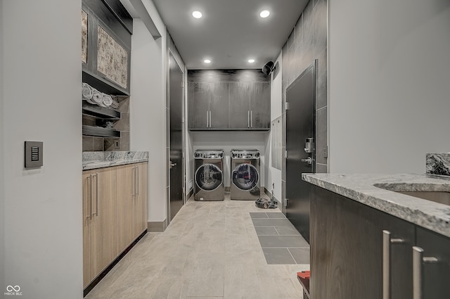 laundry room with light tile patterned floors, washer and dryer, and cabinets