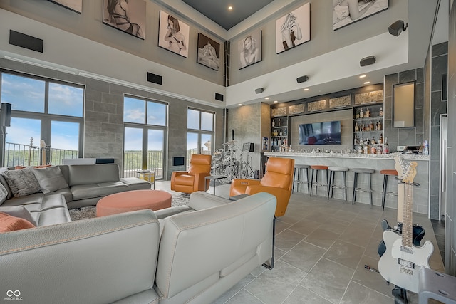 living room featuring tile patterned flooring, tile walls, indoor bar, and a high ceiling