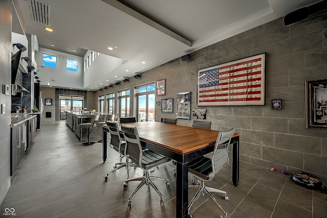 dining area featuring a high ceiling, tile walls, and tile patterned floors