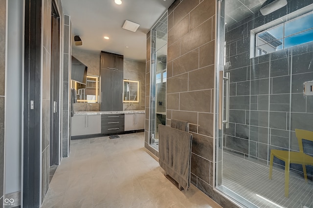 bathroom with a shower with shower door, tile patterned flooring, and tile walls