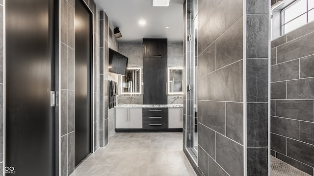 bathroom featuring tiled shower, tile walls, and tile patterned floors