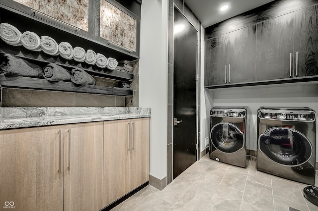 clothes washing area with cabinets, separate washer and dryer, and light tile patterned flooring