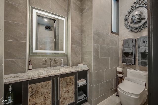 bathroom featuring tile patterned flooring, tile walls, toilet, and vanity