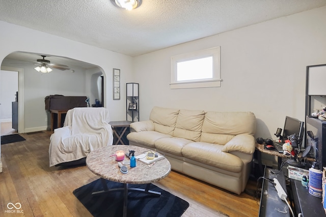 living room featuring ceiling fan, a textured ceiling, and wood-type flooring