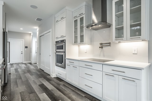 kitchen featuring wall chimney range hood, dark hardwood / wood-style flooring, white cabinets, and black electric stovetop